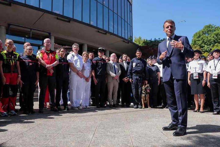 Presidente da França, Emmanuel Macron, conversa com pessoas que farão a segurança do local — Foto: Christian Hartmann / POOL / AFP