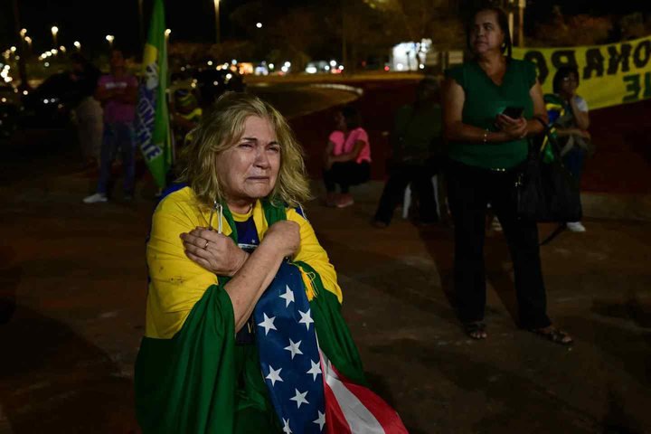 Apoiadores do ex-presidente brasileiro Jair Bolsonaro rezam em frente ao seu condomínio em Brasília, em 11 de setembro de 2025. — Foto: Pablo Porciúncula/AFP