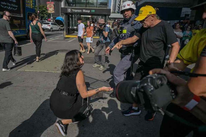 Mulher foi empurrada e precisou ser retirada pela Policia após se envolver em confusão com manifestantes de direita — Foto: AFP