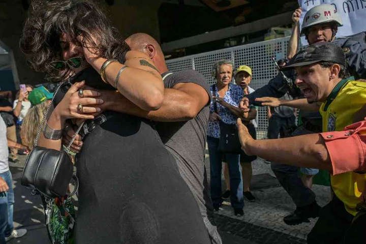 Mulher foi empurrada e precisou ser retirada pela Policia após se envolver em confusão com manifestantes de direita — Foto: AFP